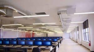 Espace de travail avec plusieurs ordinateurs en rangée dans un bureau moderne.